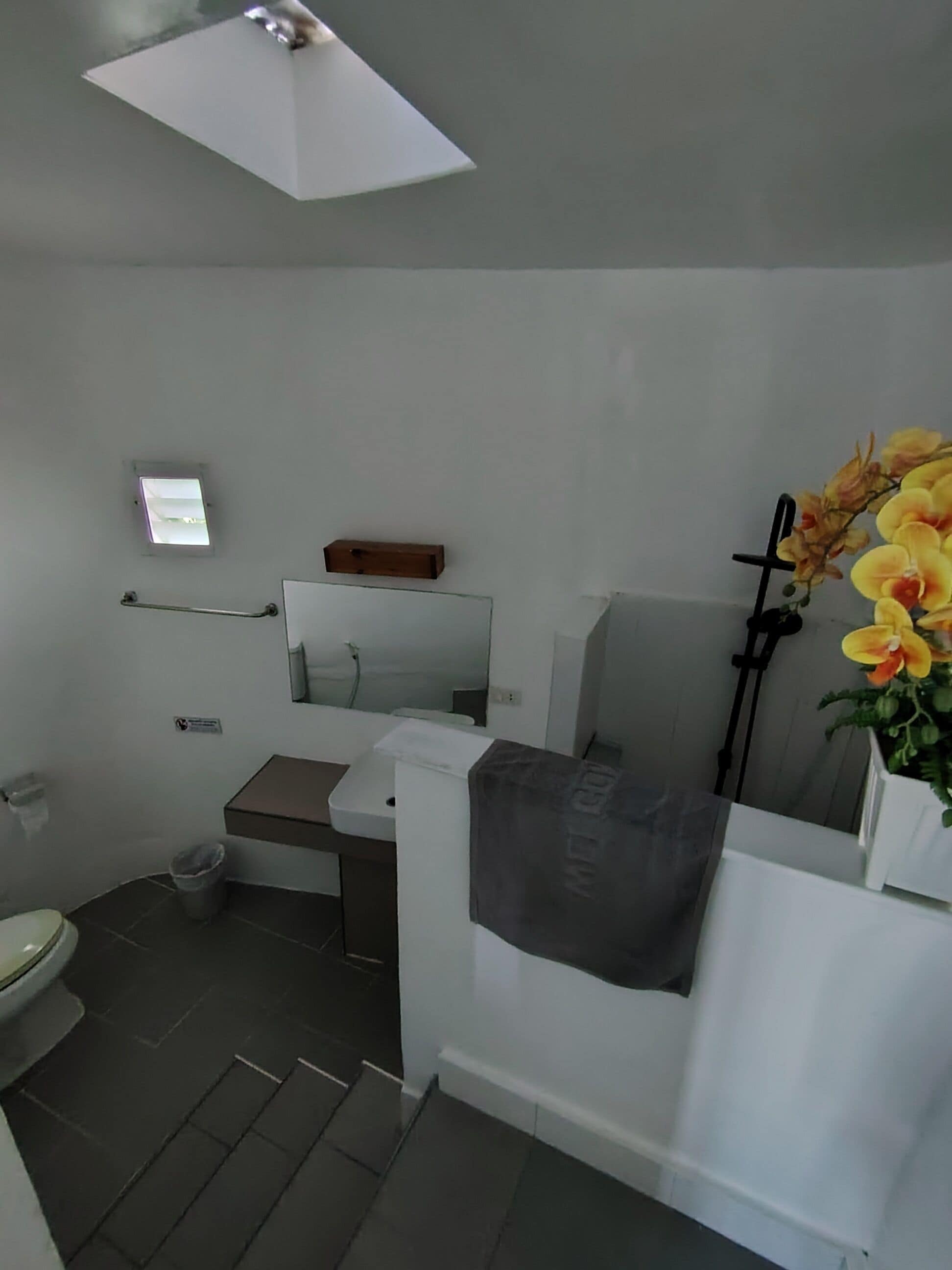 A bathroom with a toilet, sink, mirror, and a small window.