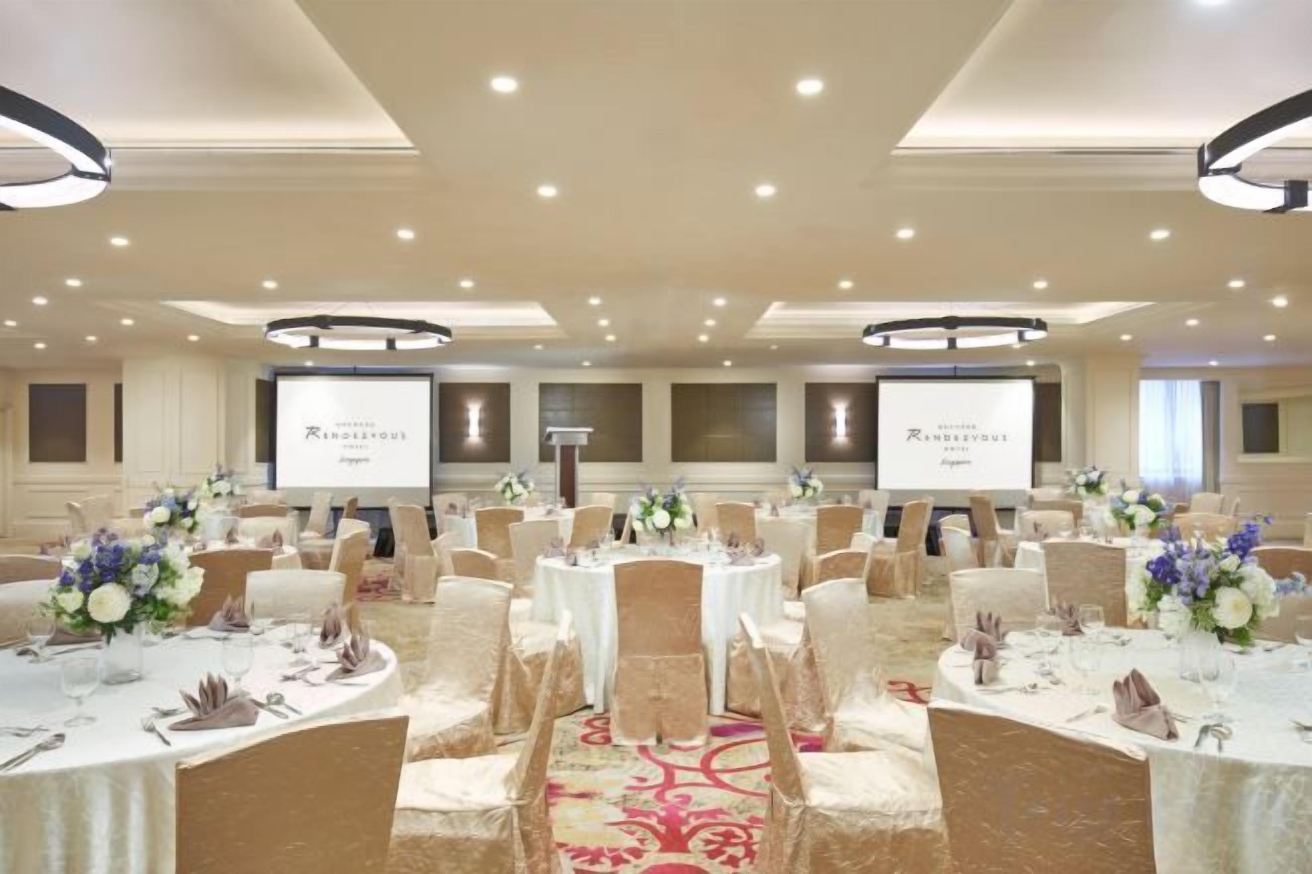 Une salle de banquet avec des tables rondes, des chaises et des centres de table floraux.