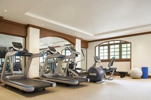 Ein Fitnessraum mit Laufbändern, Crosstrainern und Übungsbällen.