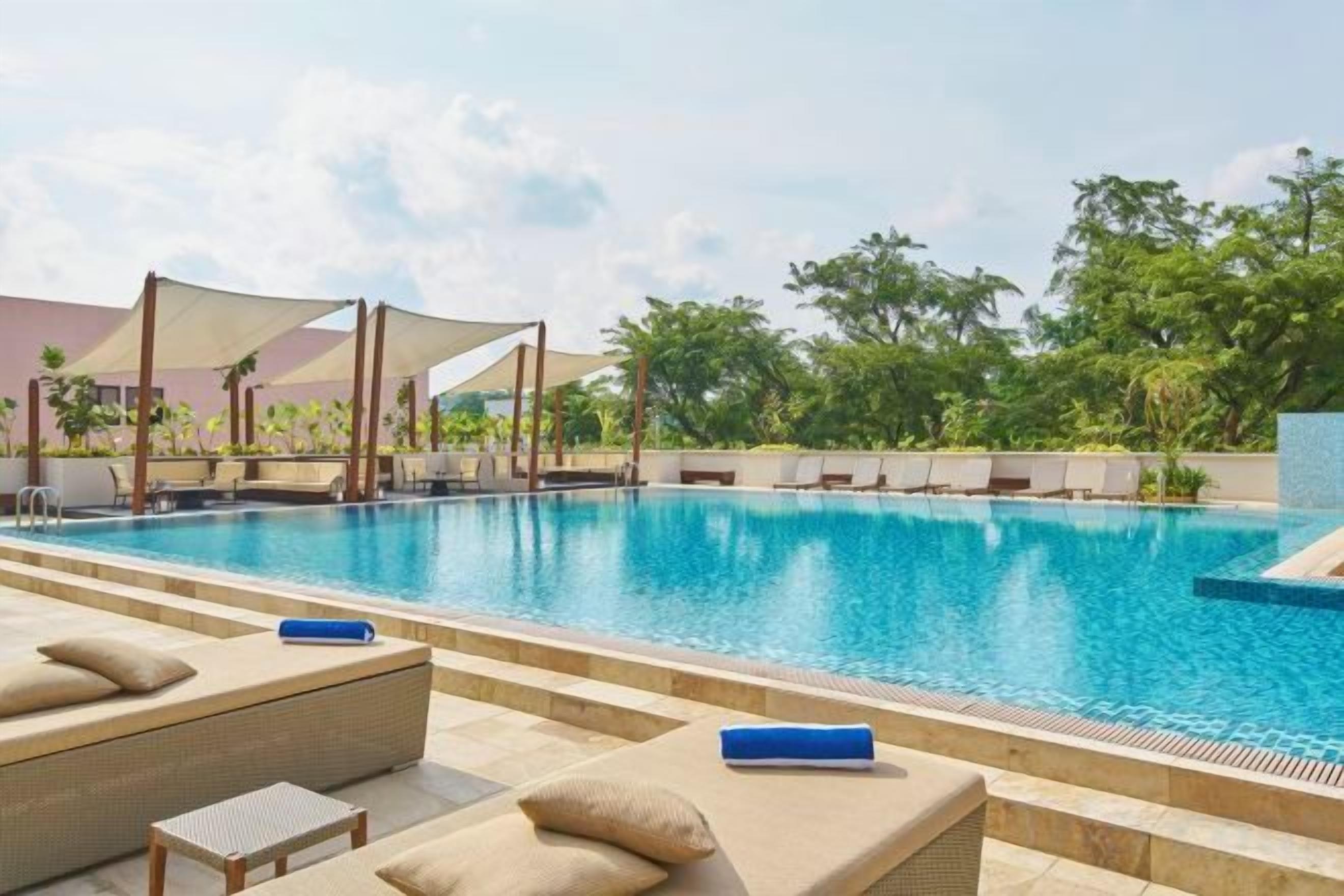 Une piscine avec des chaises longues et un espace ombragé.