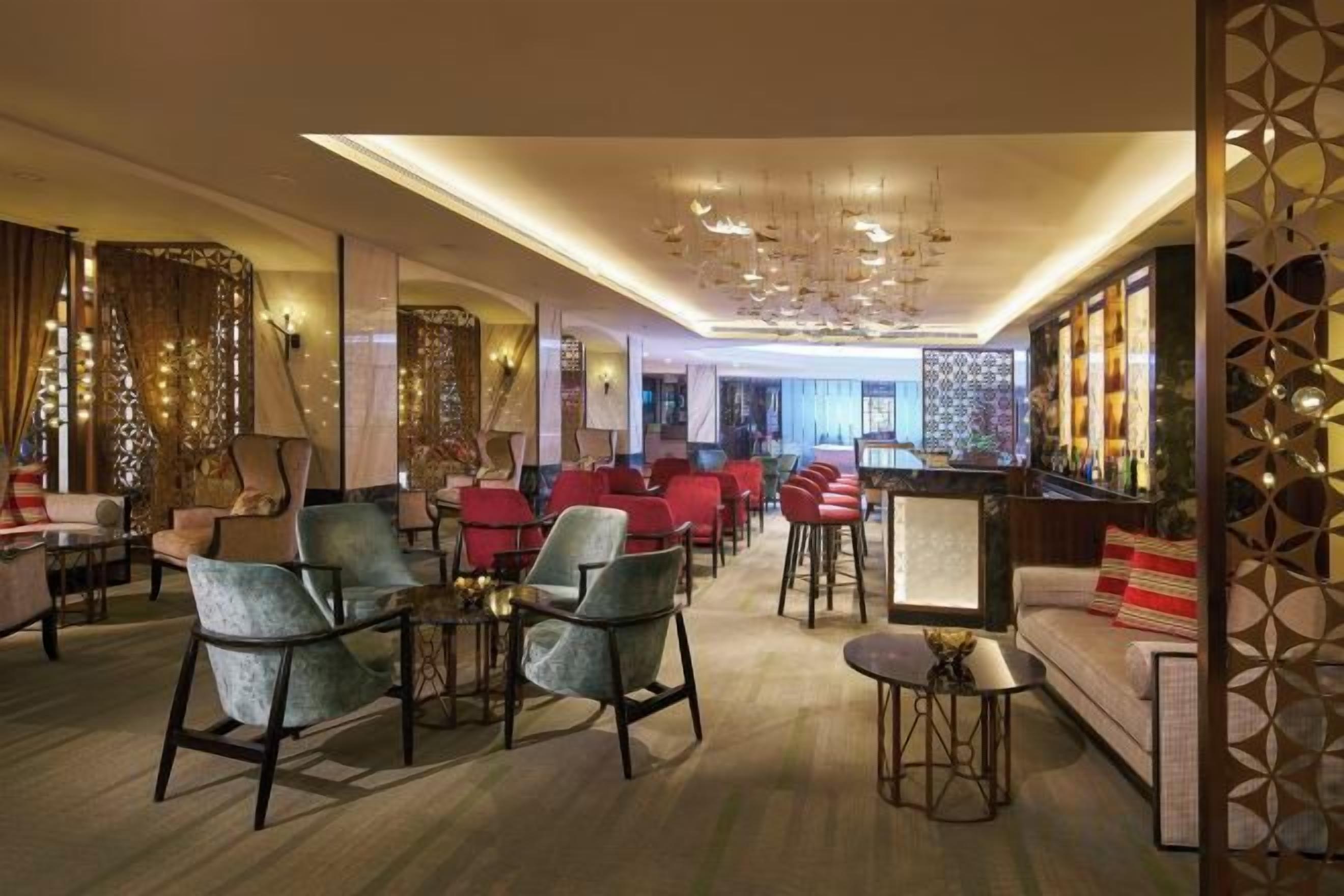 Un hall de hotel con zonas de estar, un bar y vistas a la ciudad.