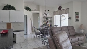 A modern kitchen with white cabinets, a dining area with a glass table, and a living room with a brown sofa. -   Great 4-bedroom house in Englewood with pool, on a canal, 15 min. from beach. (Englewood)