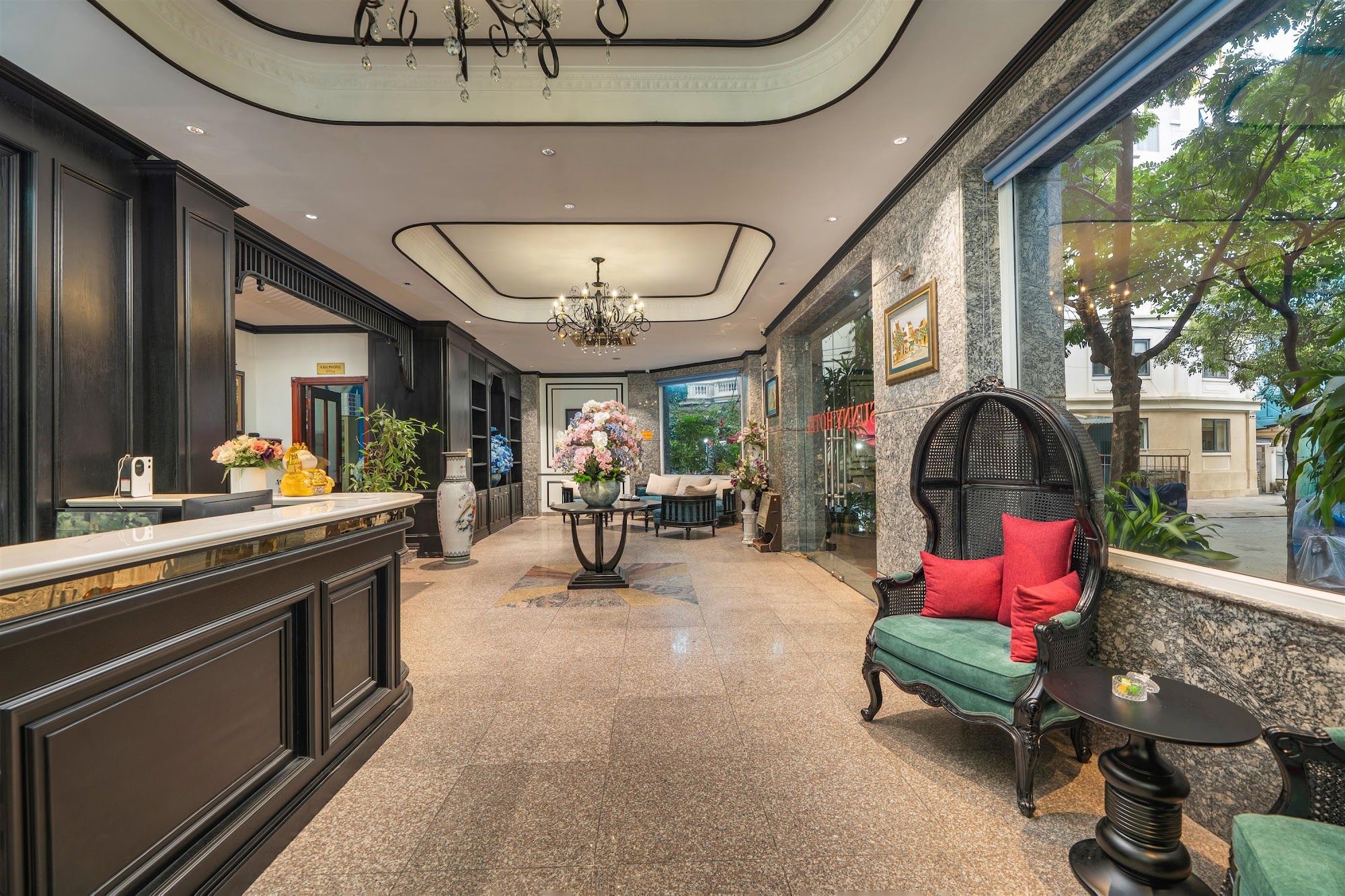 A hotel lobby with a reception desk, seating area, and a view of the outdoors.