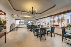 A spacious dining area with tables and chairs, a chandelier, and large windows offering a city view. - Sunny Hotel Ha Noi (Hanoi)