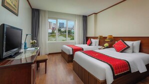 Habitación de hotel con dos camas, televisión, escritorio y vistas a la ciudad.