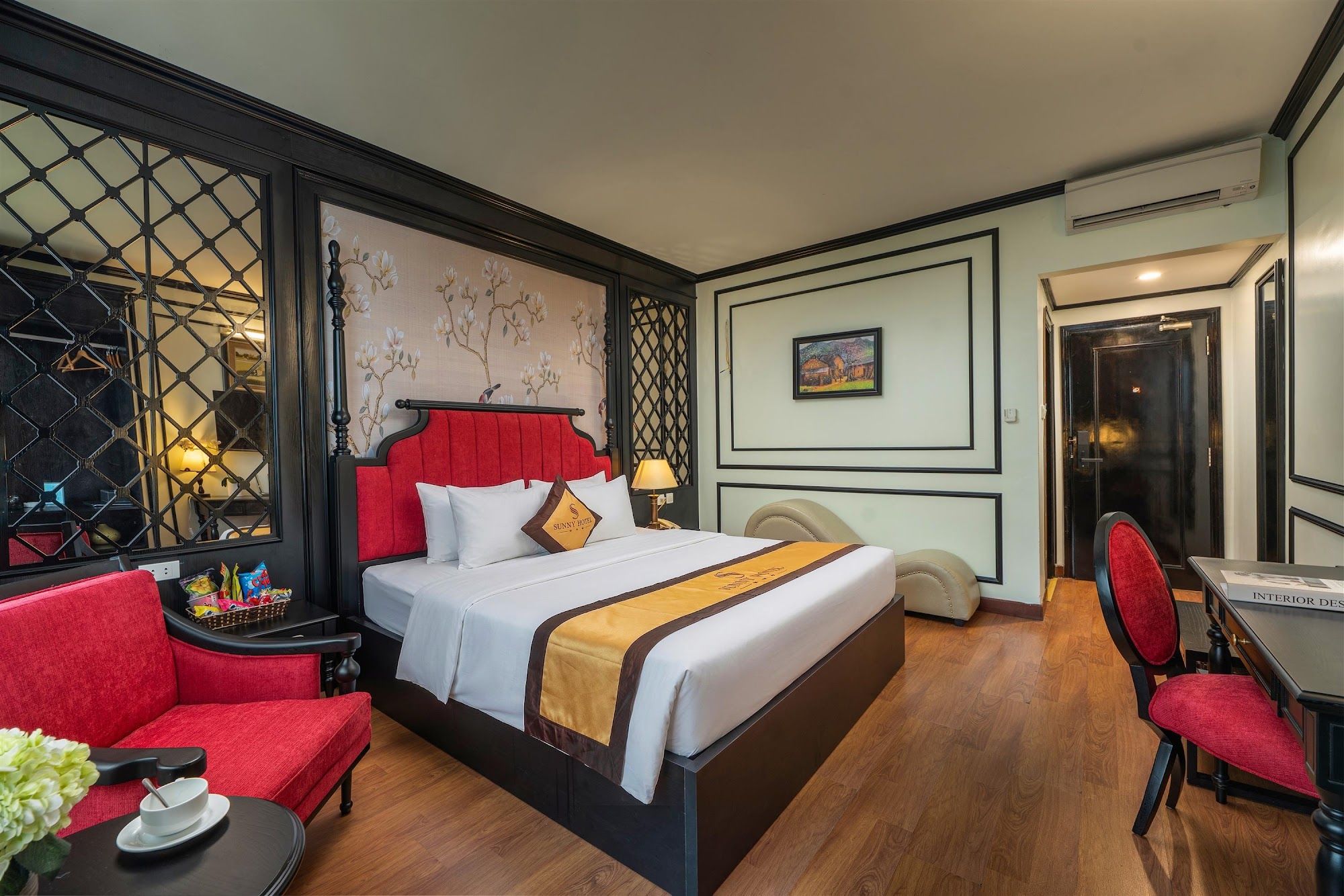A hotel room with a bed, a desk, a chair, and a window with a decorative screen.