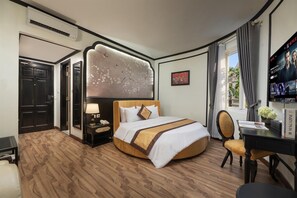 Een hotelkamer met een bed, een bureau, een stoel, een televisie en een schilderij aan de muur.