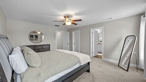 Une chambre à coucher avec un lit, un ventilateur de plafond, une commode et un miroir.