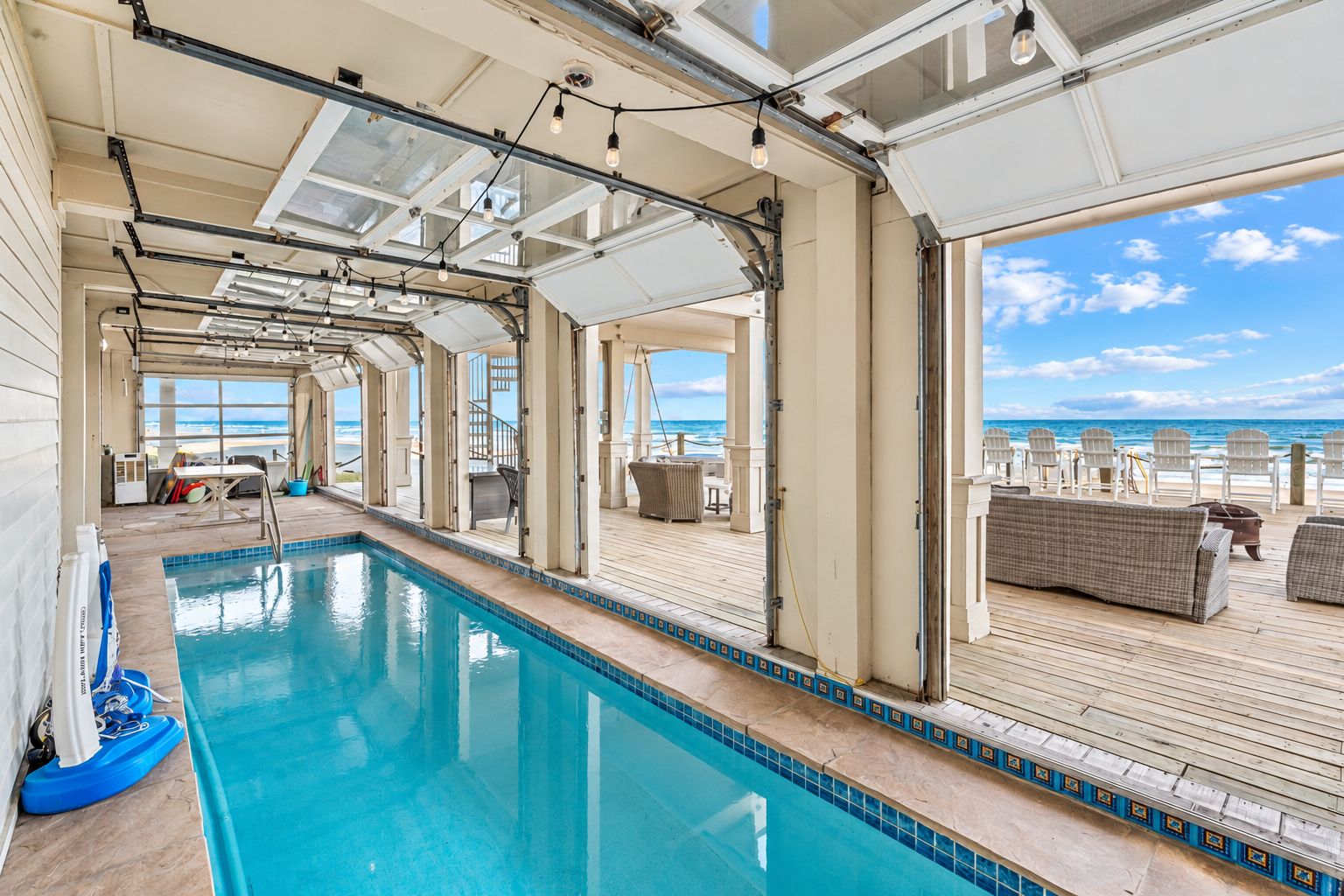 Ein Poolbereich mit freiem Blick auf den Ozean, Liegestühle und eine überdachte Sitzgelegenheit.