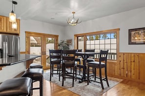 A kitchen with a central island, wooden cabinets, a stainless steel refrigerator, and a chandelier.