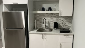 A compact kitchen with a stainless steel refrigerator, a sink, and a microwave.