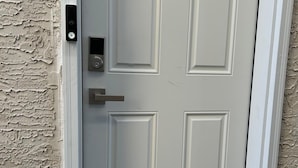 A white door with a keypad lock and a doorbell.