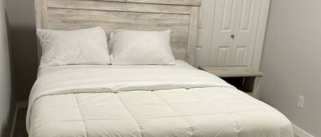 A bed with a wooden headboard and footboard, a white comforter, and two pillows.