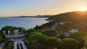 A coastal landscape with a clear view of the sea, a road leading to a building, and a hill with vegetation. - Large 2-room luxury residence for 4 people with swimming pool and air conditioning. (LES ISSAMBRES)