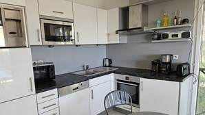 A modern kitchen with white cabinets, a built-in microwave, a coffee maker, and a toaster. - Large 2-room luxury residence for 4 people with swimming pool and air conditioning. (LES ISSAMBRES)