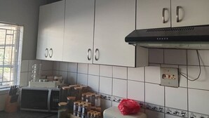 A kitchen with white cabinets, a microwave, and a red object on the counter. - Welcoming Bed & Breakfast with Air Conditioning in the Heart of Windhoek (Windhoek)