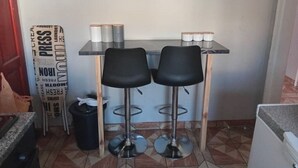 A small kitchen area with two black bar stools, a countertop, and a shelf with glassware and jars. - Welcoming Bed & Breakfast with Air Conditioning in the Heart of Windhoek (Windhoek)