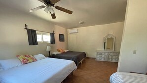 Una habitación con dos camas, ventilador de techo, cómoda y ventana con cortinas.