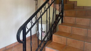 Una escalera con barandillas de metal negro y baldosas de terracota.