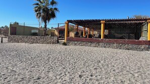 Una playa con un área cercada, una palmera y un edificio de fachada amarilla y roja.