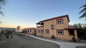 Un bâtiment doté d’un toit recouvert de tuiles rouges et de murs de couleur beige, avec de nombreuses fenêtres et des unités de climatisation.