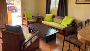 Una sala de estar con un sofá, sillas, una mesa de centro y una mesa de comedor.