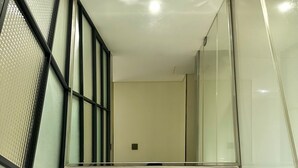 Une salle de bain moderne avec un grand miroir, un lavabo blanc et une cloison en verre.