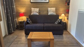 A cozy living room with a dark sofa, two decorative pillows, a wooden coffee table, and a framed picture on the wall.
