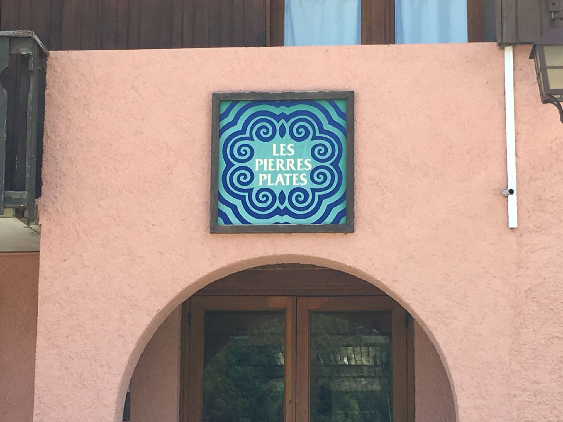 Et skilt med teksten "LES PIERRES PLATES" på en bygnings facade.