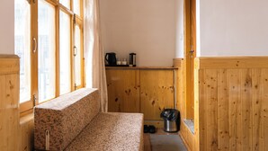 En inredning med träpanel, en bänk, en papperskorg och ett fönster med gardiner.
