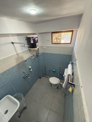 Un baño con inodoro, lavamanos, ducha y un ventilador en la pared.