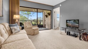 A living room with a sofa, armchairs, a TV on a stand, and a ceiling fan. - Upstay 2BR Golfer s Retreat w Patio Ventura Resort (Orlando)