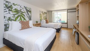 Une chambre d’hôtel avec deux lits, une petite kitchenette et une grande fenêtre donnant sur l’extérieur.