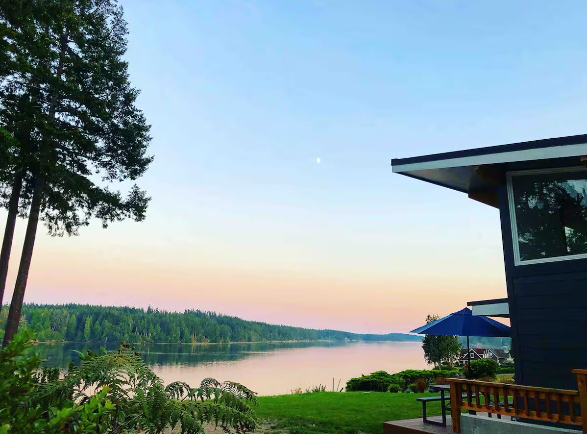 A lakeside view with a house, a dock, and a clear sky.