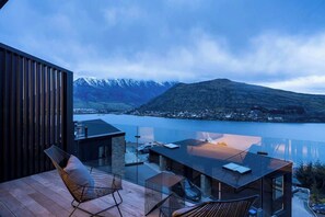 Une terrasse extérieure moderne offrant une vue sur un lac et des montagnes.