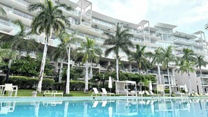 Un hôtel moderne doté de nombreux balcons, d’une piscine et de palmiers.