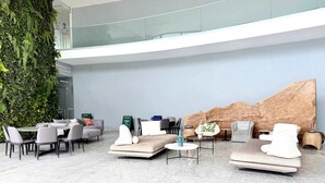 Un hall d’entrée moderne avec un plafond haut, un mur végétal et un espace détente comprenant des canapés et des fauteuils.