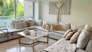 Un salon moderne avec un canapé d’angle, une table basse et une décoration murale en macramé.