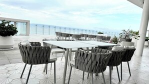 A terrace with a table and chairs, overlooking a body of water. - Bolongo 3BR Your Exclusive Oceanfront Escape (Punta de Mita)
