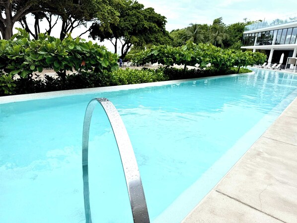 A swimming pool with a metal arch in the center, surrounded by lush greenery and a modern building in the background. - Bolongo 3BR Your Exclusive Oceanfront Escape (Punta de Mita)