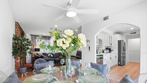A dining area with a glass table, clear chairs, and a vase of flowers.