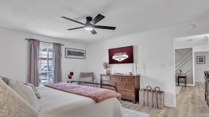 Un dormitorio con cama, ventilador de techo, cómoda y cartel de bienvenida.