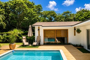 Une maison moderne dotée d’une piscine, d’un espace salon extérieur et d’une végétation luxuriante.