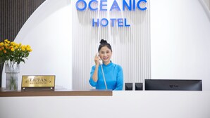 A reception desk at Oceanic Hotel with a sign reading "Lê Tân Reception" and a vase of yellow flowers. - Oceanic Hotel Vung Tau (Ho Chi Minh City)