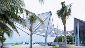 An outdoor area with a modern geometric structure, palm trees, and a paved walkway. - Oceanic Hotel Vung Tau (Ho Chi Minh City)