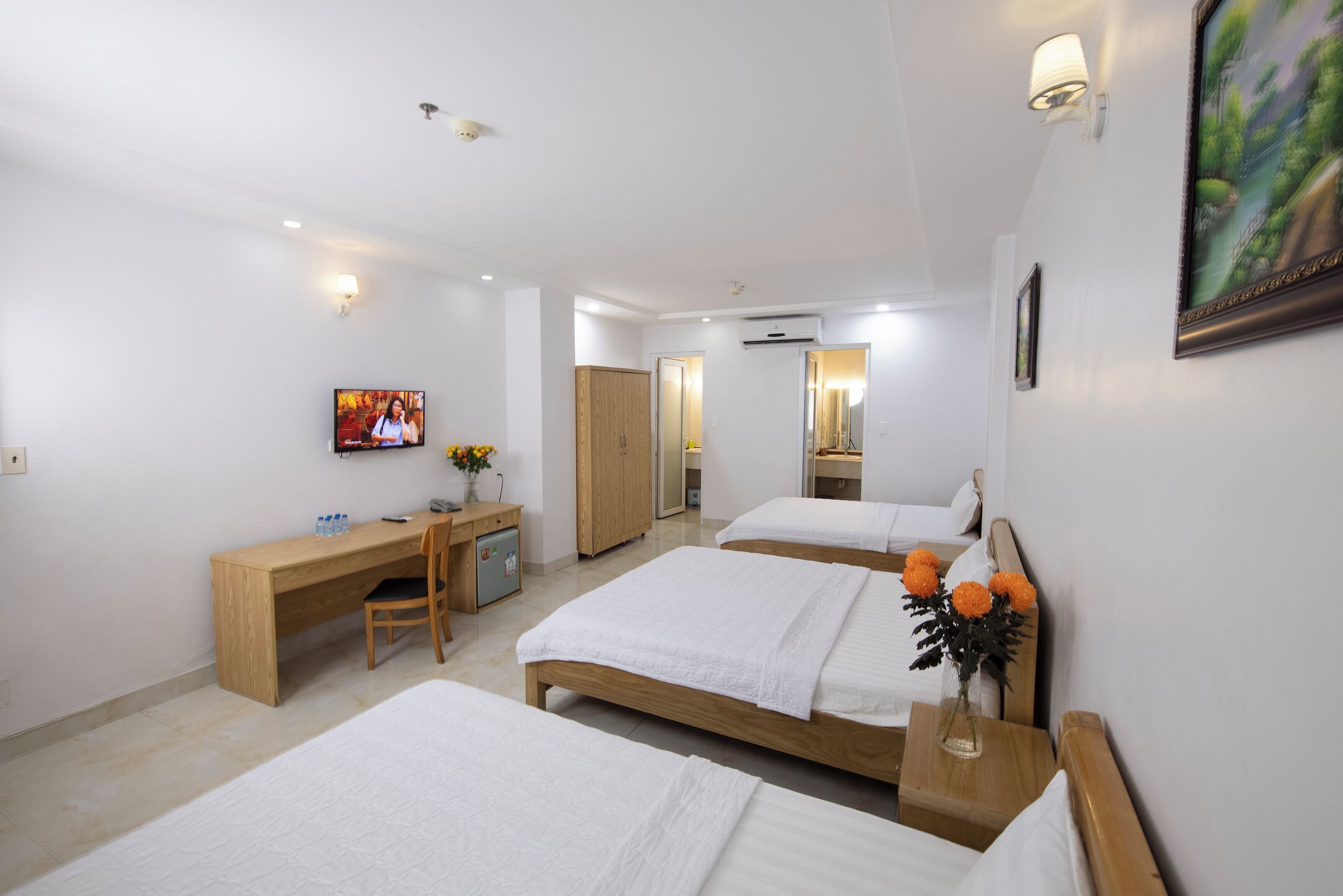 Ein Hotelzimmer mit zwei Betten, einem Schreibtisch, einem Fernseher und einem durchgegangenen Badezimmer.