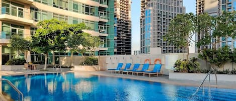 Una piscina al aire libre, sillones reclinables de piscina