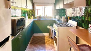Una cocina con armarios verdes, un microondas, una estufa y un lavaplatos.