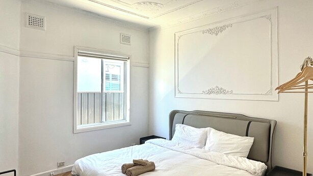 Un dormitorio moderno con una cama, una mesita de noche, una lámpara de pie y una ventana.