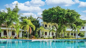 Um hotel com piscina, rodeado por vegetação exuberante e um céu azul límpido.